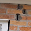 A brick wall displaying stair-step cracks and messy tuckpointing on a Kanata home